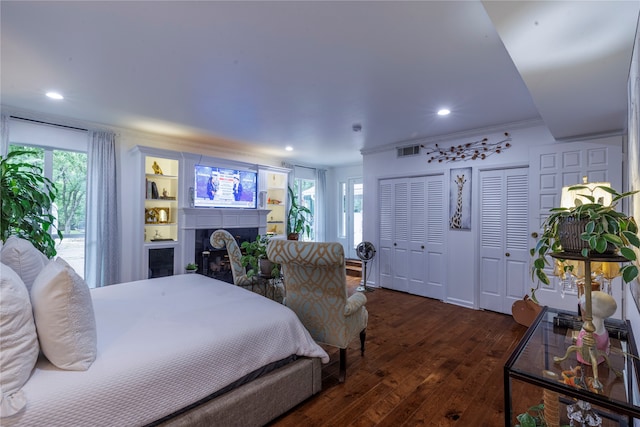 bedroom with multiple windows, ornamental molding, two closets, and dark wood-type flooring