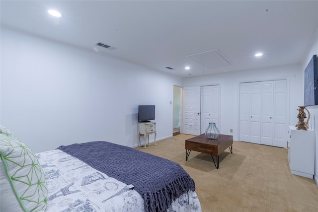 bedroom featuring multiple closets and light colored carpet