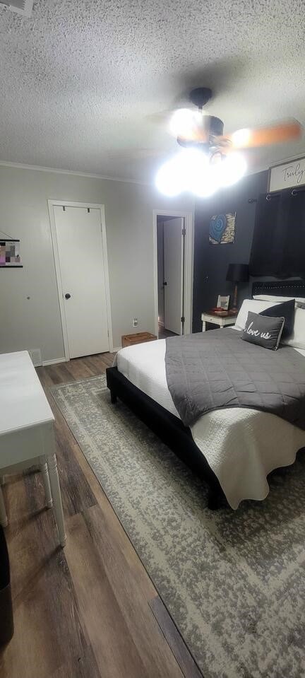 bedroom featuring dark hardwood / wood-style flooring, ceiling fan, and a textured ceiling