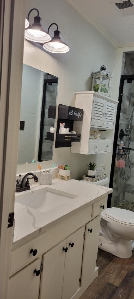 bathroom with walk in shower, hardwood / wood-style flooring, large vanity, and toilet