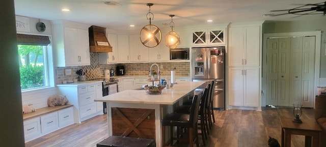 kitchen with decorative light fixtures, appliances with stainless steel finishes, custom range hood, and dark hardwood / wood-style floors