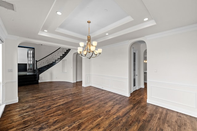 spare room with a tray ceiling, a chandelier, and dark wood-type flooring