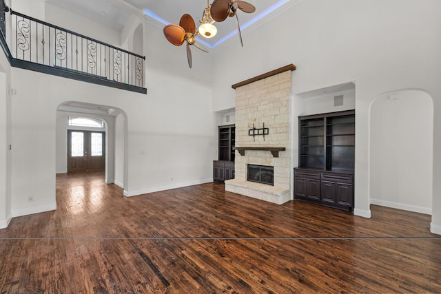 unfurnished living room featuring a high ceiling, a fireplace, and dark wood-type flooring