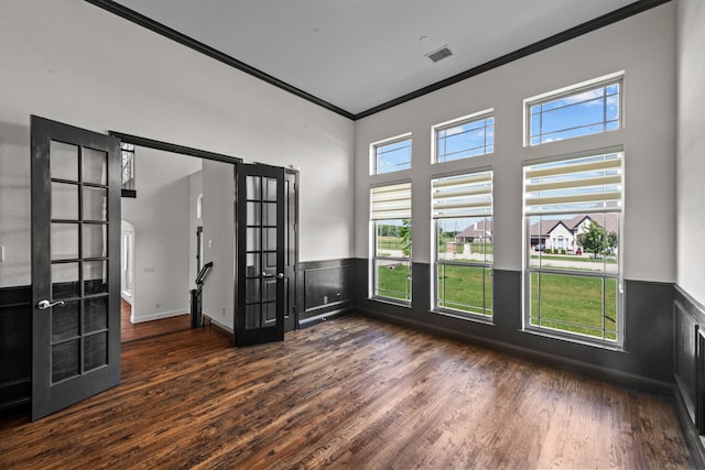 spare room featuring dark hardwood / wood-style floors, plenty of natural light, ornamental molding, and french doors