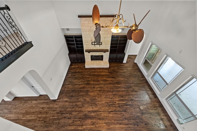 living room with brick wall, an inviting chandelier, a high ceiling, and dark hardwood / wood-style floors