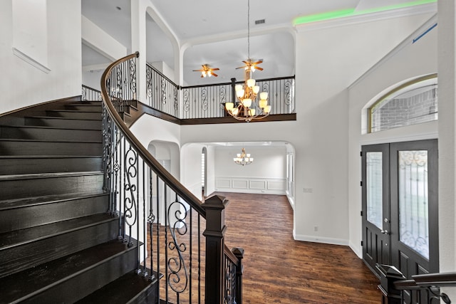 entrance foyer featuring french doors, a notable chandelier, dark hardwood / wood-style flooring, a high ceiling, and ornamental molding