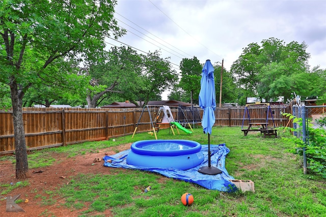 view of yard featuring a playground, a trampoline, and a pool