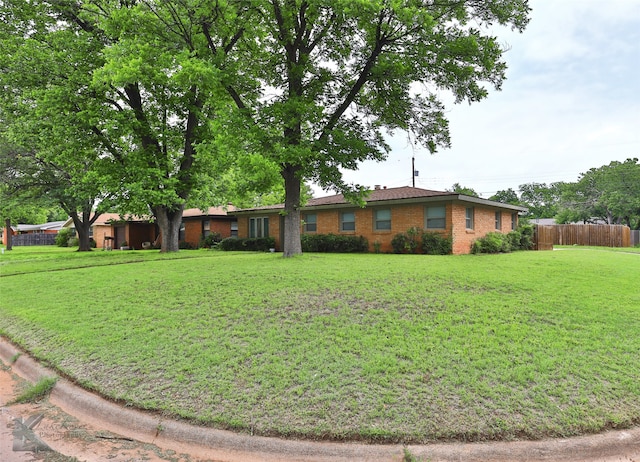 ranch-style home featuring fence, a front lawn, and brick siding