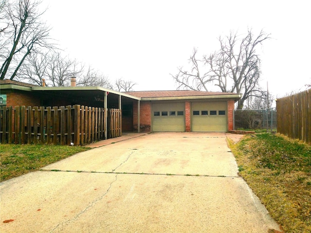 garage featuring fence and concrete driveway