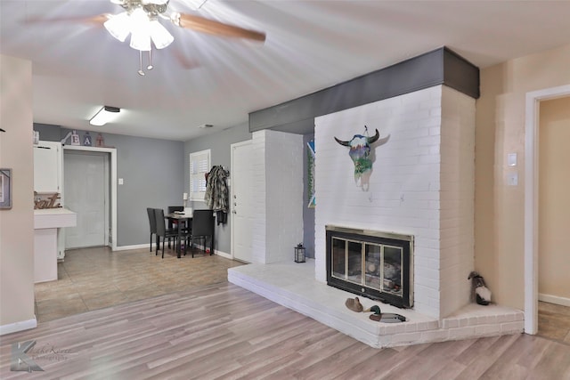 living room with a fireplace, light hardwood / wood-style floors, and ceiling fan