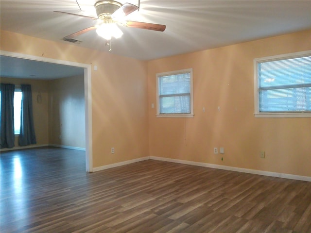 unfurnished room with dark wood-type flooring, a ceiling fan, visible vents, and baseboards