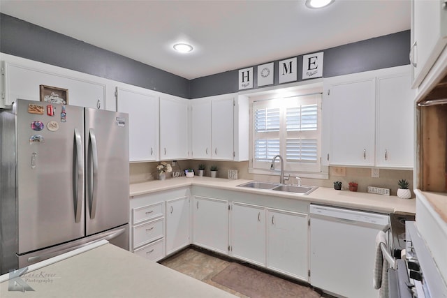 kitchen with stainless steel refrigerator, white cabinetry, dishwasher, sink, and decorative backsplash