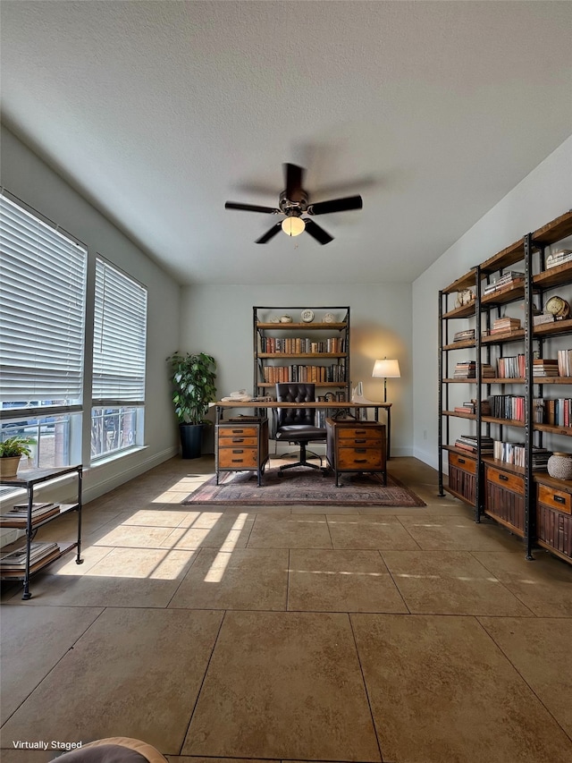 unfurnished office with ceiling fan and a textured ceiling