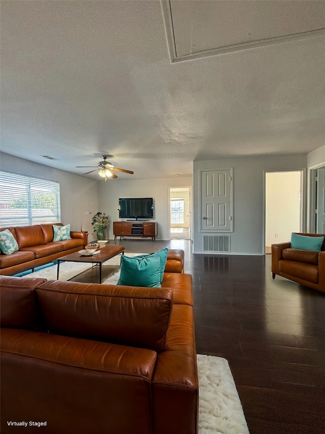 living room with dark wood-type flooring, a textured ceiling, and ceiling fan