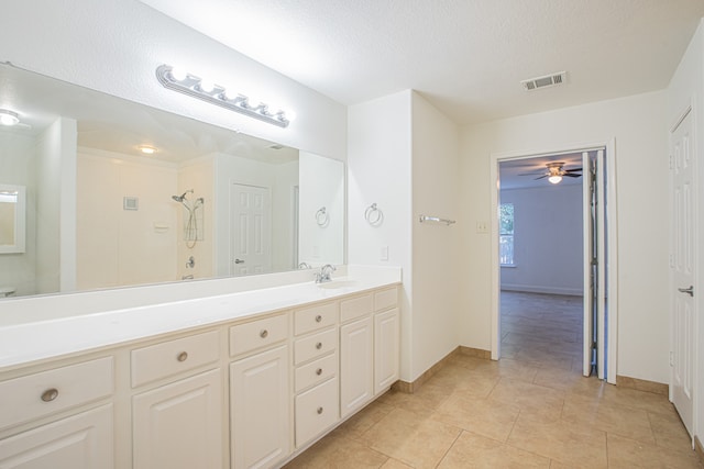 bathroom with tile patterned floors, ceiling fan, vanity, a textured ceiling, and walk in shower