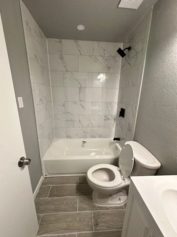 full bathroom with tiled shower / bath combo, vanity, tile floors, and toilet