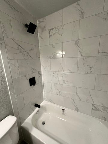 bathroom featuring tiled shower / bath and toilet