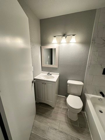 full bathroom featuring oversized vanity, tiled shower / bath, and toilet