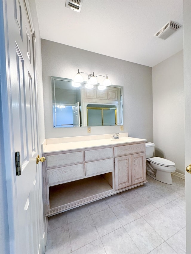 bathroom with vanity with extensive cabinet space, toilet, and tile floors