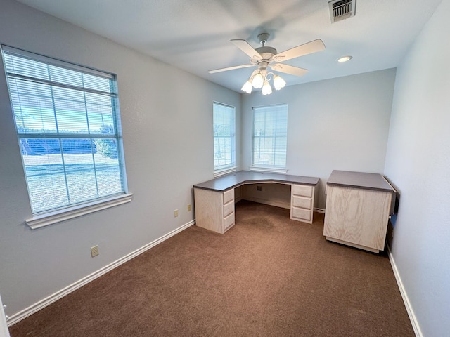 unfurnished office with ceiling fan and dark colored carpet