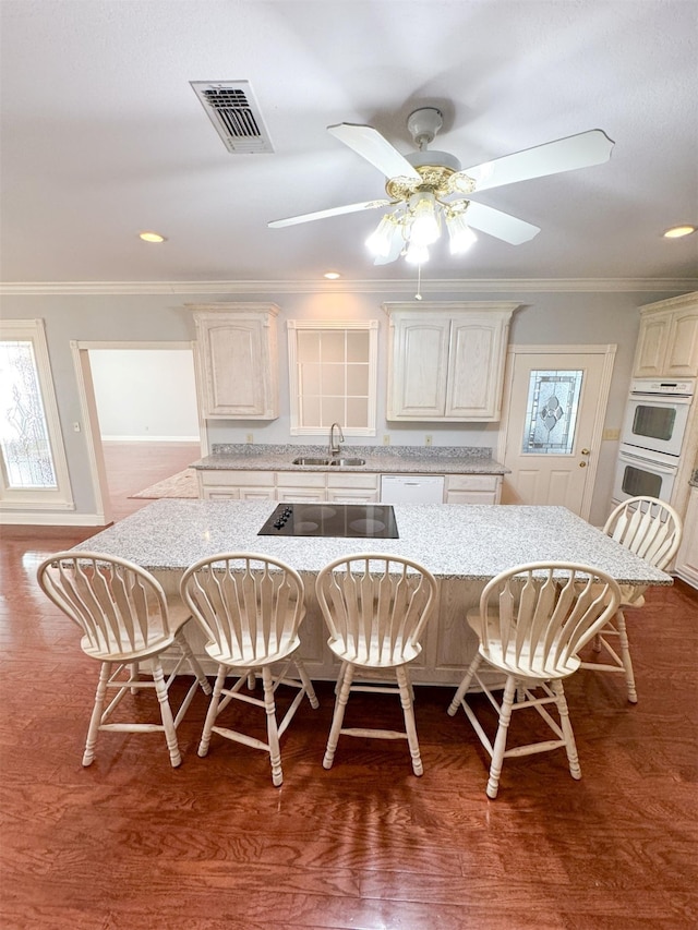 kitchen with hardwood / wood-style flooring, a kitchen bar, and light stone counters