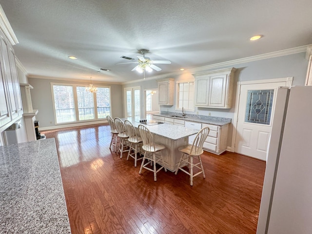 dining space with ceiling fan with notable chandelier, ornamental molding, dark hardwood / wood-style floors, and sink