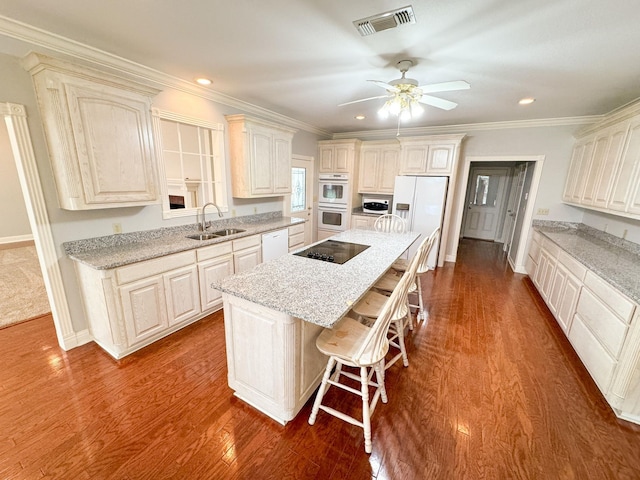 kitchen with a center island, a kitchen breakfast bar, dark hardwood / wood-style floors, sink, and ceiling fan