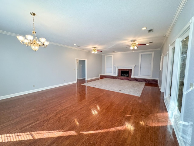 unfurnished living room featuring ornamental molding, dark hardwood / wood-style flooring, ceiling fan with notable chandelier, and a fireplace