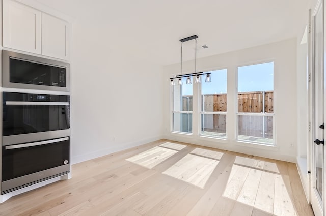 unfurnished dining area featuring a notable chandelier and light hardwood / wood-style floors