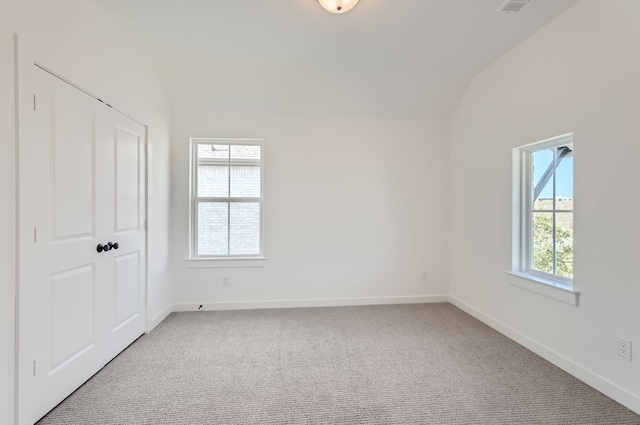 empty room featuring vaulted ceiling, light carpet, and a healthy amount of sunlight