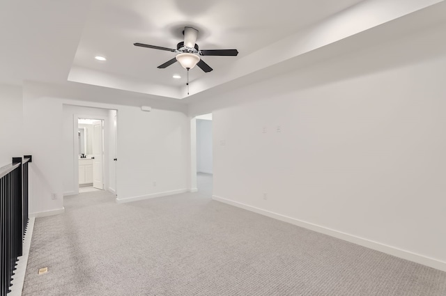 carpeted empty room with ceiling fan and a tray ceiling