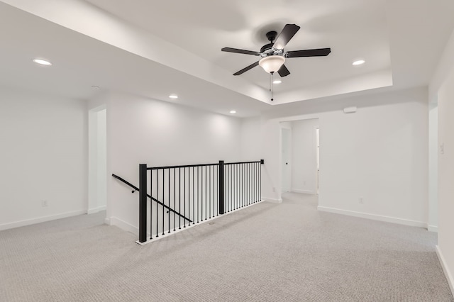 carpeted empty room featuring a tray ceiling and ceiling fan