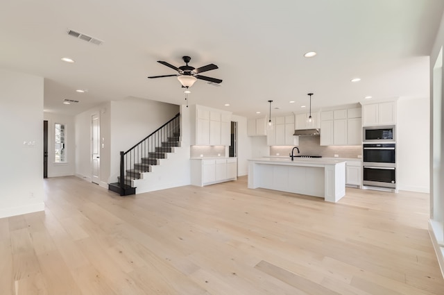 unfurnished living room featuring light hardwood / wood-style floors, sink, and ceiling fan