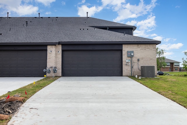 view of front facade featuring a garage, central AC unit, and a front lawn