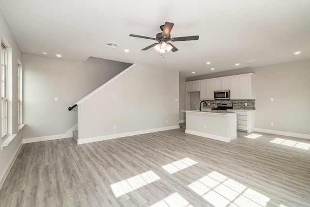 unfurnished living room featuring sink, ceiling fan, and light hardwood / wood-style floors