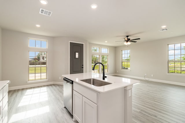 kitchen with light hardwood / wood-style flooring, stainless steel dishwasher, a center island with sink, sink, and ceiling fan