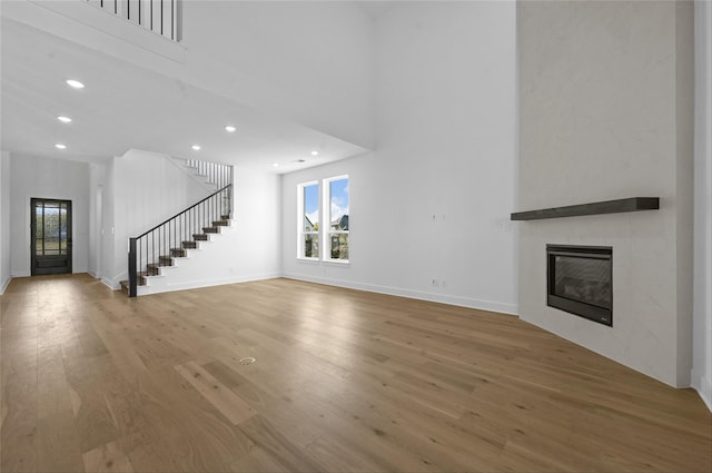 unfurnished living room featuring a fireplace, a high ceiling, and hardwood / wood-style flooring