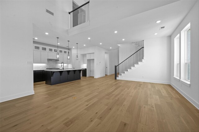 unfurnished living room featuring sink and light hardwood / wood-style flooring