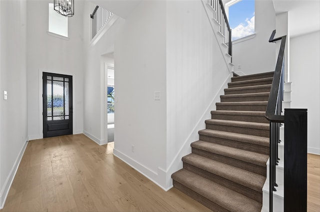 foyer entrance featuring a wealth of natural light, light hardwood / wood-style floors, a high ceiling, and an inviting chandelier