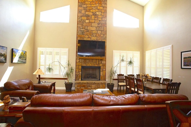 living room with hardwood / wood-style floors, a stone fireplace, and a towering ceiling