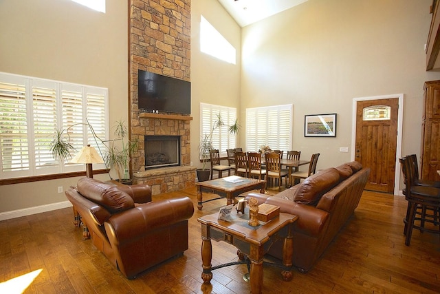 living room with high vaulted ceiling, a wealth of natural light, a fireplace, and dark hardwood / wood-style flooring