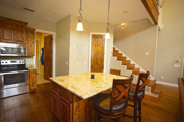 kitchen with pendant lighting, dark hardwood / wood-style flooring, a center island, light stone counters, and stainless steel appliances