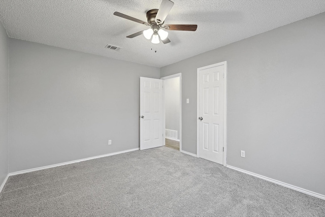 spare room featuring a textured ceiling, ceiling fan, and carpet