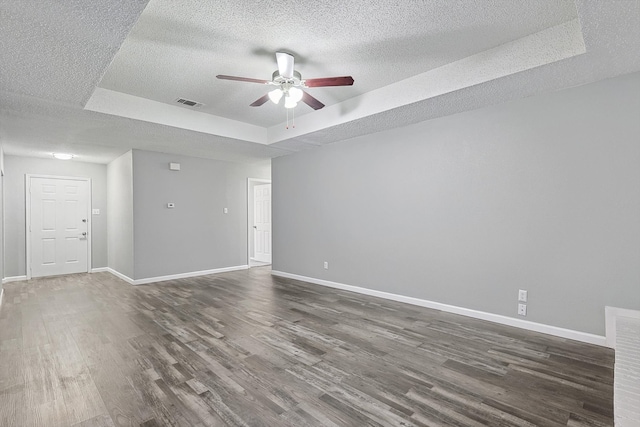 empty room featuring dark hardwood / wood-style flooring, ceiling fan, a raised ceiling, and a textured ceiling