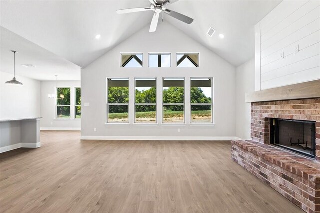 living room featuring a fireplace, light wood-type flooring, high vaulted ceiling, and ceiling fan