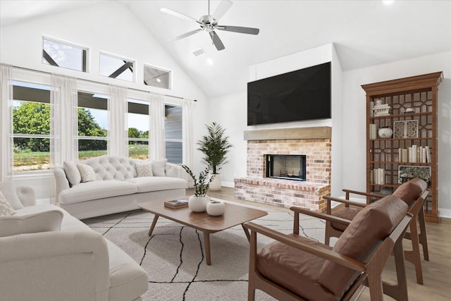 living room with a fireplace, light hardwood / wood-style floors, high vaulted ceiling, and ceiling fan