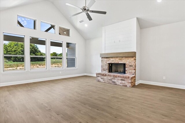 unfurnished living room with a fireplace, a wealth of natural light, ceiling fan, and wood-type flooring