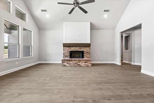 unfurnished living room featuring hardwood / wood-style flooring, ceiling fan, lofted ceiling, and a fireplace