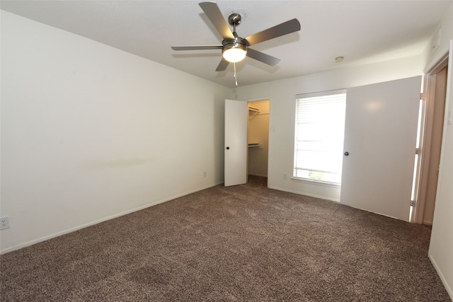 unfurnished bedroom featuring a spacious closet, a closet, ceiling fan, and carpet