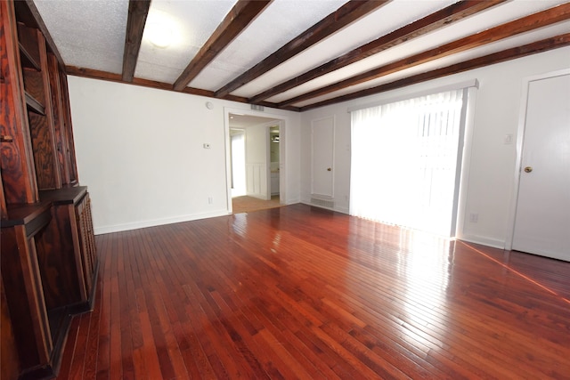 spare room featuring dark hardwood / wood-style floors and beam ceiling